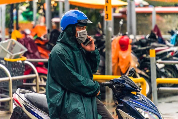 Ho Chi Minh şehri, Vietnam - 08 Ağustos 2020: Yerel halk Emart süpermarketinden alışveriş yapıyor, tıbbi maskeler takıyor, yağmurda motosiklet sürüyor ve Covid-19 salgınında sosyal mesafeyi koruyorlar.