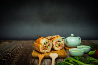 Yemek molasında. Meşhur Vietnam yemekleri Banh mi thit ve sıcak çay, hammaddeyle doldurulmuş ekmeğin popüler sokak yemekleri: domuz eti, jambon, börek, yumurta ve taze ottur. Tipik Vietnam sandviçi.