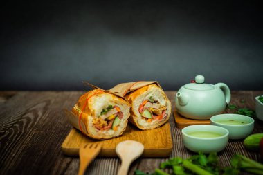 Yemek molasında. Meşhur Vietnam yemekleri Banh mi thit ve sıcak çay, hammaddeyle doldurulmuş ekmeğin popüler sokak yemekleri: domuz eti, jambon, börek, yumurta ve taze ottur. Tipik Vietnam sandviçi.