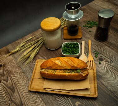 Yemek molasında. Ünlü Vietnam yemekleri Banh mi thit ve sade kahveydir, hammaddeyle doldurulmuş ekmeğin popüler sokak yemekleri: domuz eti, jambon, börek, yumurta ve taze ottur. Tipik Vietnam sandviçi.