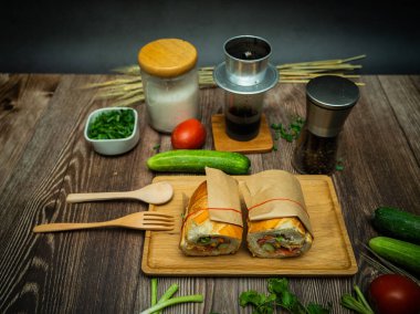Yemek molasında. Ünlü Vietnam yemekleri Banh mi thit ve sade kahveydir, hammaddeyle doldurulmuş ekmeğin popüler sokak yemekleri: domuz eti, jambon, börek, yumurta ve taze ottur. Tipik Vietnam sandviçi.