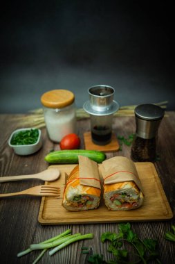 Yemek molasında. Ünlü Vietnam yemekleri Banh mi thit ve sade kahveydir, hammaddeyle doldurulmuş ekmeğin popüler sokak yemekleri: domuz eti, jambon, börek, yumurta ve taze ottur. Tipik Vietnam sandviçi.