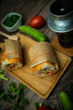 Yemek molasında. Ünlü Vietnam yemekleri Banh mi thit ve sade kahveydir, hammaddeyle doldurulmuş ekmeğin popüler sokak yemekleri: domuz eti, jambon, börek, yumurta ve taze ottur. Tipik Vietnam sandviçi.