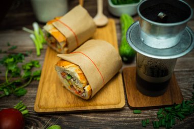 Yemek molasında. Ünlü Vietnam yemekleri Banh mi thit ve sade kahveydir, hammaddeyle doldurulmuş ekmeğin popüler sokak yemekleri: domuz eti, jambon, börek, yumurta ve taze ottur. Tipik Vietnam sandviçi.