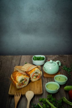 Yemek molasında. Meşhur Vietnam yemekleri Banh mi thit ve sıcak çay, hammaddeyle doldurulmuş ekmeğin popüler sokak yemekleri: domuz eti, jambon, börek, yumurta ve taze ottur. Tipik Vietnam sandviçi.