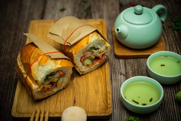 Yemek molasında. Meşhur Vietnam yemekleri Banh mi thit ve sıcak çay, hammaddeyle doldurulmuş ekmeğin popüler sokak yemekleri: domuz eti, jambon, börek, yumurta ve taze ottur. Tipik Vietnam sandviçi.