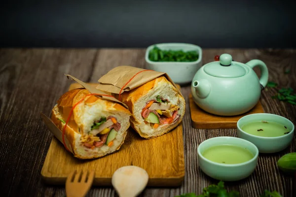 Yemek molasında. Meşhur Vietnam yemekleri Banh mi thit ve sıcak çay, hammaddeyle doldurulmuş ekmeğin popüler sokak yemekleri: domuz eti, jambon, börek, yumurta ve taze ottur. Tipik Vietnam sandviçi.