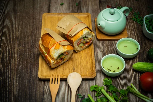 Yemek molasında. Meşhur Vietnam yemekleri Banh mi thit ve sıcak çay, hammaddeyle doldurulmuş ekmeğin popüler sokak yemekleri: domuz eti, jambon, börek, yumurta ve taze ottur. Tipik Vietnam sandviçi.