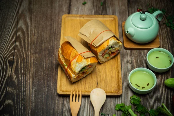 Yemek molasında. Meşhur Vietnam yemekleri Banh mi thit ve sıcak çay, hammaddeyle doldurulmuş ekmeğin popüler sokak yemekleri: domuz eti, jambon, börek, yumurta ve taze ottur. Tipik Vietnam sandviçi.