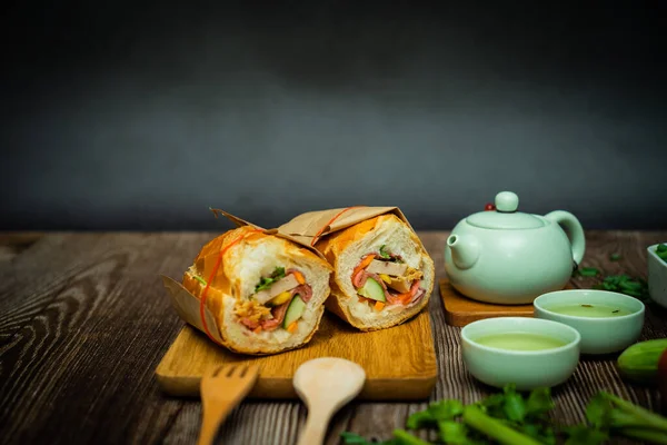 Yemek molasında. Meşhur Vietnam yemekleri Banh mi thit ve sıcak çay, hammaddeyle doldurulmuş ekmeğin popüler sokak yemekleri: domuz eti, jambon, börek, yumurta ve taze ottur. Tipik Vietnam sandviçi.