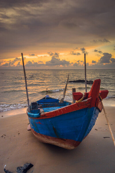 view of local fishermen pushing traditional blue wooden boats from sea to shore by traditional way,they collect fishes from nets, dawn on sea with fishing labor scene.