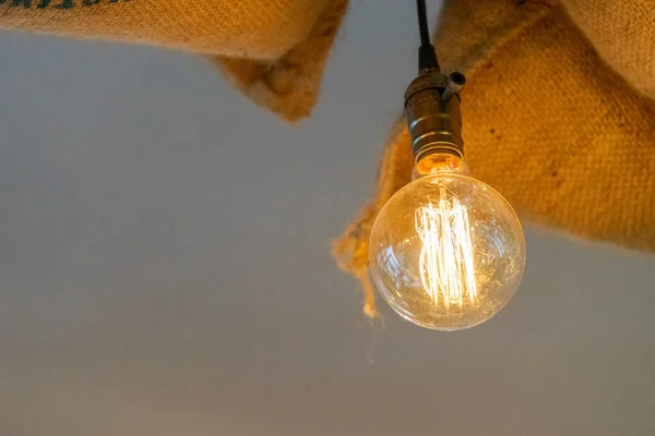Hanging Light Bulb Background - hanging incandescent light bulb and burlap bags in background. Idea, creative and business background. Selective focus.