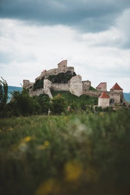 Fantastik seyahat yeri, muhteşem Rupea kalesi ön planda çimenler ve Brasov, Transilvanya, Romanya, Avrupa 'da karanlık kasvetli gökyüzü