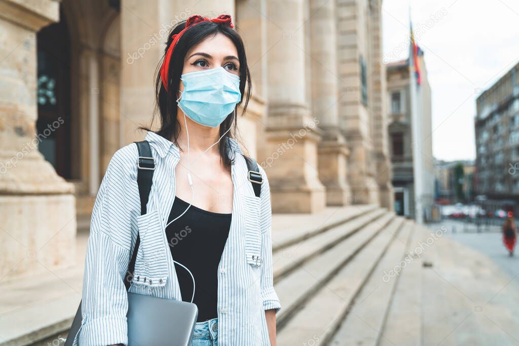 Back to School. Female student wearing protective face mask walking around university campus during COVID 19. Education, healthcare and pandemic concept