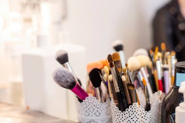 Beyaz bir cam açacağında değişik boyutlarda makyaj fırçaları, renkler, şekiller vardır. Temel, göz farı, pudra, dudaklar, elmacık kemiği yüz düzeltmesi için tasarlanmıştır. Seçici yumuşak odak