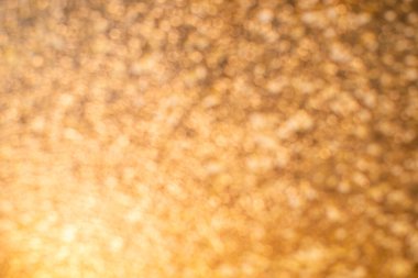 Turuncu bir ışık hüzmesi, altın ve parlak bir arkaplanda yanıp sönüyor. Doku parlıyor ve parlıyor, metin ve reklam için boş bir yer, güneşin parlaklığı, masanın pürüzsüz yüzeyinde yansıma.