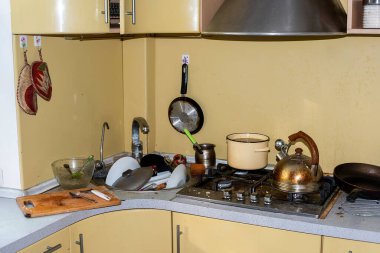 Pis ve pis bir mutfak, yağlı bir soba, lavaboda bir dağ dolusu yıkanmamış bulaşık. Sağlıksız koşullar, evin dağınıklığı. Çaydanlık ve pirzolalar yanmış ve plaka takılmış.