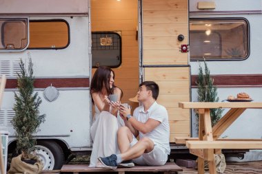 Güzel bir çift sabahın erken saatlerinde kahvaltıda sıcak içecekler içerler, konuşurlar, birbirlerine bakarlar ve gülerler. Bir karavanda dinlenme kavramı. Yeni Evli İçin Balayı