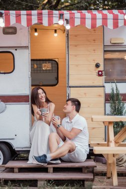 Güzel bir çift sabahın erken saatlerinde kahvaltıda sıcak içecekler içerler, konuşurlar, birbirlerine bakarlar ve gülerler. Bir karavanda dinlenme kavramı. Yeni Evli İçin Balayı