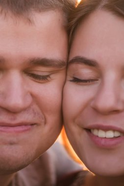 Birbirine aşık bir çiftin ekstra yakın portresi, güzel erkek ve kız birbirlerinin yanaklarına dokunuyor, gözleri kapalı, gülümsüyor ve gülüyor. Aile ilişkilerinde yakınlık, güven ve aşk kavramı.