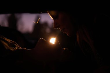 Arka koltuktaki arabada sevgililerin silueti var. Sevgili çift geceyi birlikte geçirmek için akşam karanlığında emekli oldu. Kız, aşağıda yatan adamı öpmek ve gözlerinin içine bakmak için eğildi. Tutku 