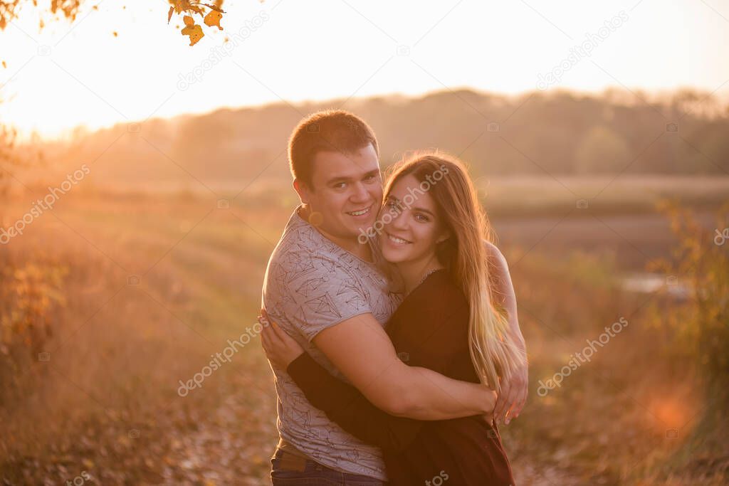 Beautiful couple in love hugs, laughs and looks at the camera against the setting sun. The concept of intimacy, trust and love in family relationships. close up portrait of lovers. Travel vacations