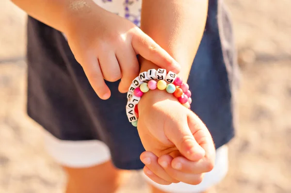 DIY bracelet for children from square, round, colored beads with the words \
