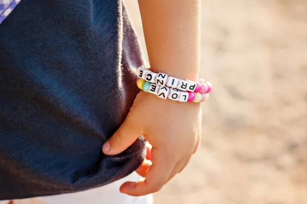 DIY bracelet for children from square, round, colored beads with the words \