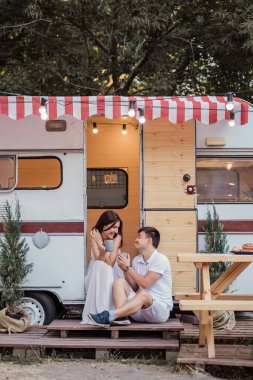 Güzel bir çift sabahın erken saatlerinde kahvaltıda sıcak içecekler içerler, konuşurlar, birbirlerine bakarlar ve gülerler. Bir karavanda dinlenme kavramı. Yeni Evli İçin Balayı