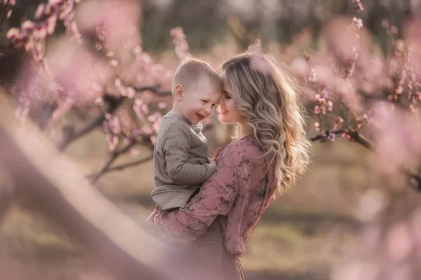 정원에서 아들을 곱슬곱슬 머리카락을 아름다운 금발의 어머니 엄마는 아이를 일으켜 — 스톡 사진