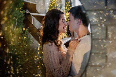 Yeni yıl portresini birbirine aşık bir çiftin aynasında kapat. Güzel bir kız genç bir adama bakar, aşıklar gülümser ve öpüşür. Işıklar altında süveter giymiş mutlu bir aile.