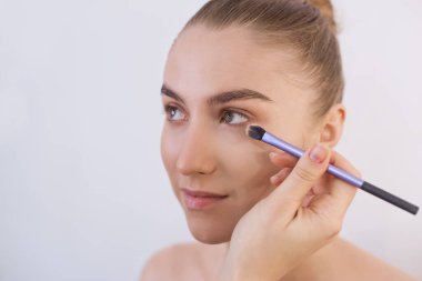 Makyajsız, temeli fırçayla atılmış güzel bir kız. Kameraya bakmayan bir modelin yakın plan portresi. Temiz bakımlı bir yüz, taze bir ten, bakım ve bakım. Boşluğu kopyala