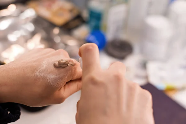 Makyajcının bir eliyle kadın eli diğer eliyle bej tonal kremi sıkıyor. Dokuları karıştırmak için paleti değiştiriyorum. Sünger ya da fırçayla cilde sürün, elinizdeki kreme batırın..