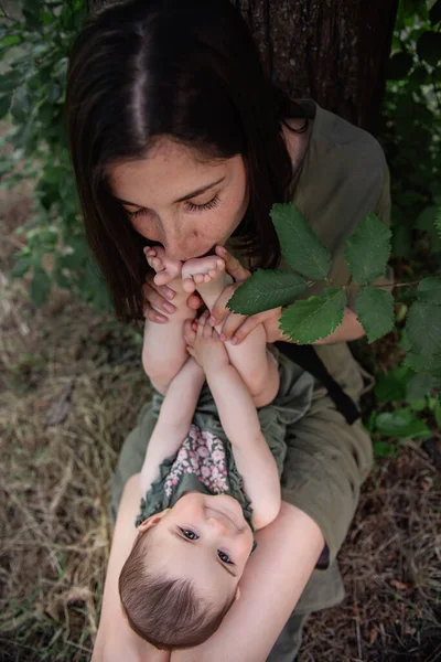 Küçük Bir Bebek Kızının Tatlı Ayaklarını Öpen Annesinin Kucağında Yatar — Stok fotoğraf