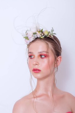 Çıplak moda parlak makyajlı genç bir kızın ekstra yakın plan portresi, saç stili, taze çiçeklerden yapılmış bir halka: piyonlar, tarla çiçekleri, okaliptüs, ranunculus. Temiz cilt. Nedime