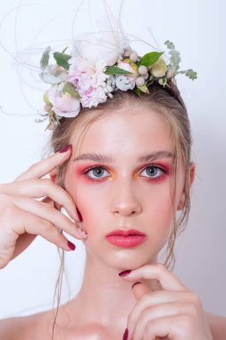 Çıplak moda parlak makyajlı genç bir kızın ekstra yakın plan portresi, saç stili, taze çiçeklerden yapılmış bir halka: piyonlar, tarla çiçekleri, okaliptüs, ranunculus. Temiz cilt. Nedime