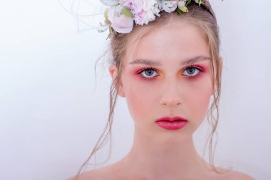 Çıplak moda parlak makyajlı genç bir kızın ekstra yakın plan portresi, saç stili, taze çiçeklerden yapılmış bir halka: piyonlar, tarla çiçekleri, okaliptüs, ranunculus. Temiz cilt. Nedime