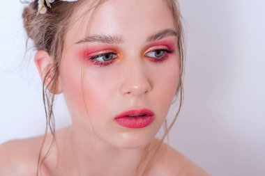 Çıplak moda parlak makyajlı genç bir kızın ekstra yakın plan portresi, saç stili, taze çiçeklerden yapılmış bir halka: piyonlar, tarla çiçekleri, okaliptüs, ranunculus. Temiz cilt. Nedime