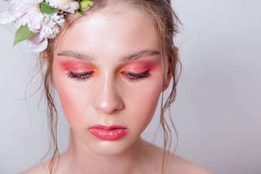 Çıplak moda parlak makyajlı genç bir kızın ekstra yakın plan portresi, saç stili, taze çiçeklerden yapılmış bir halka: piyonlar, tarla çiçekleri, okaliptüs, ranunculus. Temiz cilt. Nedime