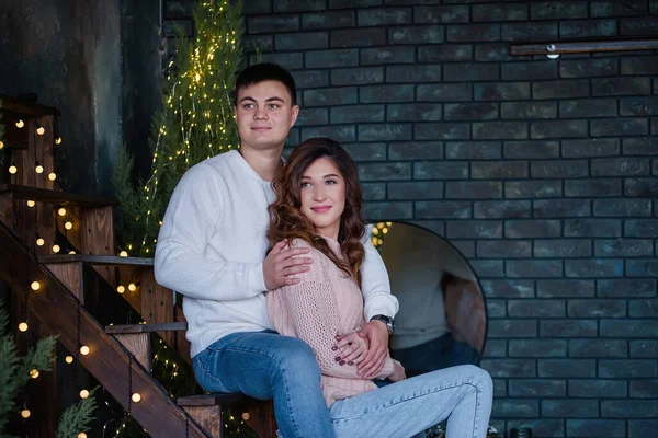 Birbirine aşık mutlu çift, ağaçlardan ve ışıklardan yapılmış çelenklerle süslenmiş el yapımı ahşap bir merdivende oturuyor. Genç bir adam güzel bir kıvırcık kızı arkadan kucaklıyor, gülüyorlar, öpüşüyorlar Noel beklentisiyle.