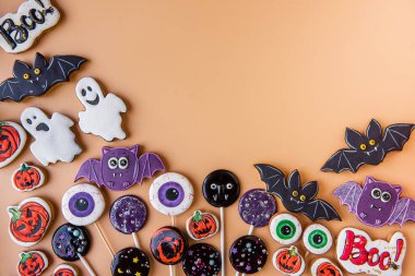 Cadılar Bayramı zencefilli ekmeği turuncu arka planda. Çocuk mamaları tatil için bir ikramdır. El yapımı lolipoplar, hayalet kurabiyeler, balkabakları, yarasalar, korkunç gözler, Boo, örümcek ağları. Boşluğu kopyala