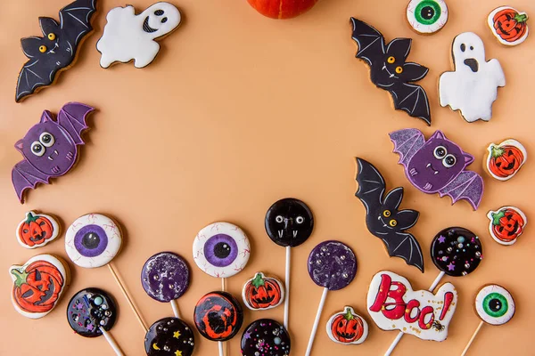 Cadılar Bayramı zencefilli ekmeği turuncu arka planda. Çocuk mamaları tatil için bir ikramdır. El yapımı lolipoplar, hayalet kurabiyeler, balkabakları, yarasalar, korkunç gözler, Boo, örümcek ağları. Boşluğu kopyala