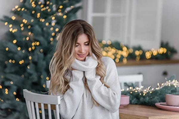 光のガーランドとクリスマスツリーで長い髪を持つ美しい巻きブロンド グレーのニットのセーターに大きな襟付きの白い笑顔の少女のクローズアップ肖像画 コピースペース テクスチャ — ストック写真