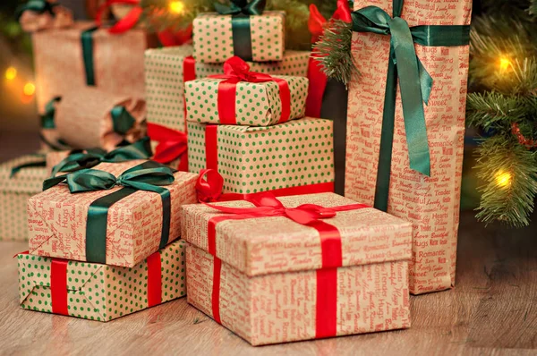Noel ağacının altında kırmızı-yeşil el işi kağıt şeritli çelenklerle süslenmiş yüksek bir hediye dağı. Yeni yıl kartı. Tatil için harika ve güzel bir manzara. Noel Baba