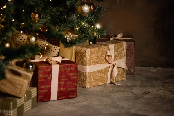 Yeni yıl tebrik kartı. Noel ağacının altında hediyelerle dolu kutular var, şenlikli altın sarısı, bordo kağıtlar, kurdelelerle bağlanmış. Uzayı kopyala Bokeh ışıkları. Noel Baba 'dan sürpriz. Metin için yer