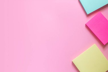 Hassas pembe arka planda üç tane renkli çıkartma. Metin için yer.