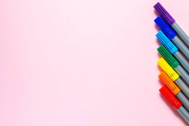 Renkli keçeli kalemlerden gökkuşağı. İşaretler sağ tarafta sıraya dizildi. Metin için yer alan düzen ve düz uzanma.