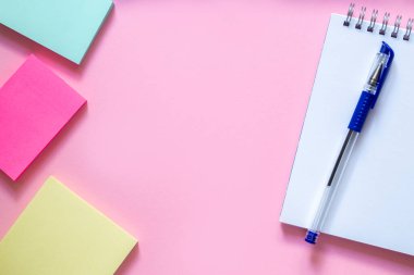 Hassas pembe arka planda üç tane renkli çıkartma. Sirchu 'ya giden spiral ve mavi kalemli beyaz bir defter. Düzen ve düz metin için yer. Okula dönüş kavramı