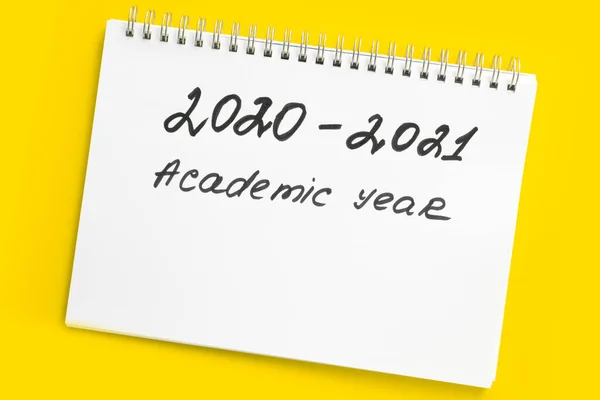 Back to school. 2020 - 2021 academic year. The inscription in a white notebook with a spiral, on a yellow background.