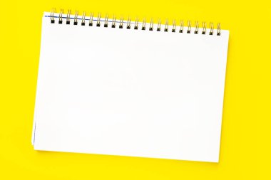 Sarı zemin üzerinde spiral olan açık bir defterin beyaz sayfası. Yerleşim ya da modelleme. Metin için boşluk ya da boşluk kopyala.